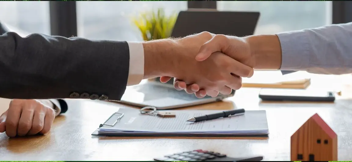 Two Professionals Shaking Hands Over Home Insurance Agreement and Calculator