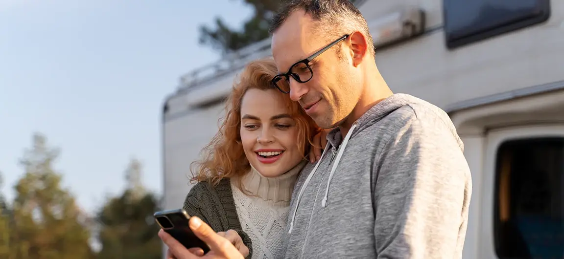 Couple Smiling at Smartphone Outdoors Near RV in White Bear Lake MN
