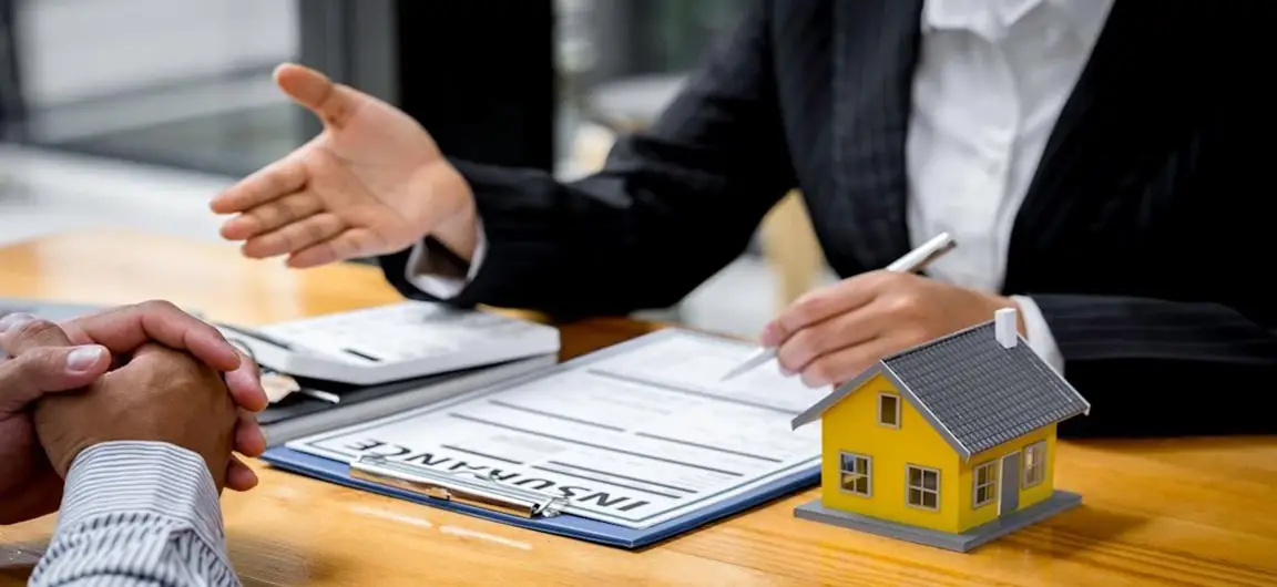 Insurance Agent Discussing Policy at Desk with Miniature House